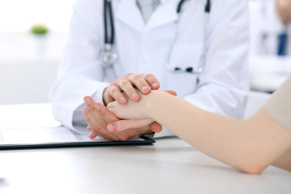 Doctor in a white coat holding a patient's hand