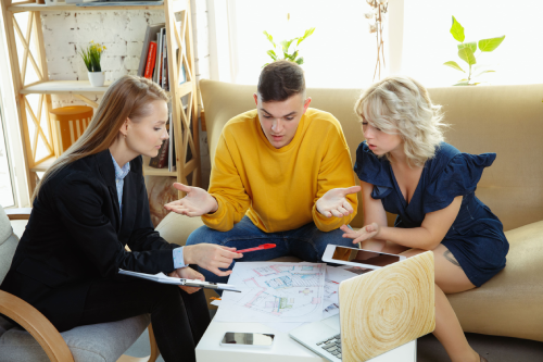 Three people discussing documents around a coffee table