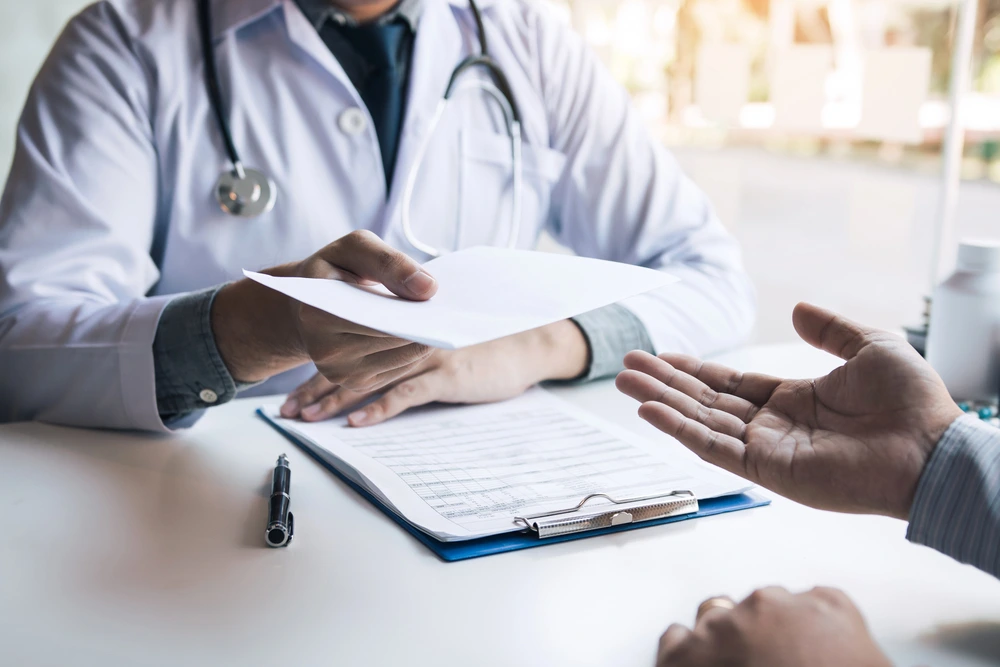 Doctor handing a clipboard with a form to a patient