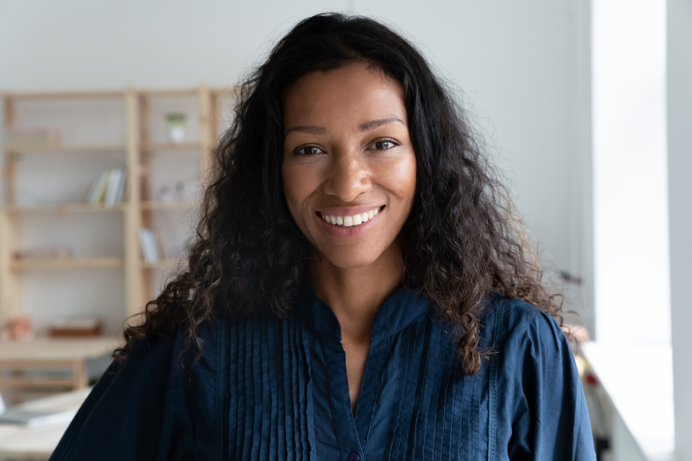 Portrait of a smiling woman with long dark curly hair in a navy blouse
