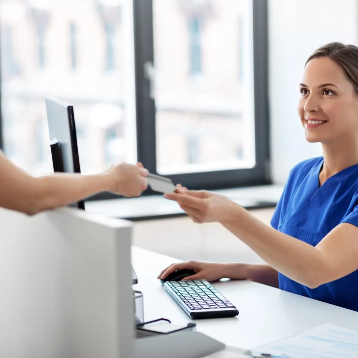Receptionist handing a document to a patient at a front desk