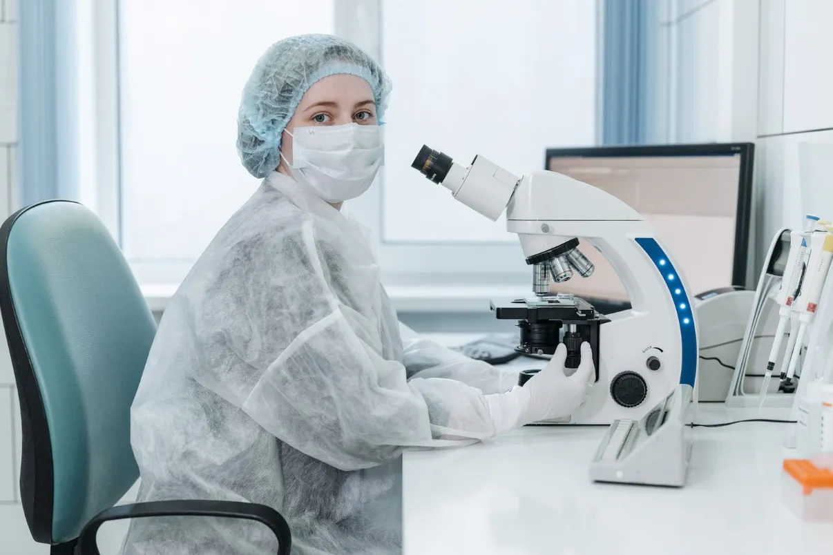 Lab technician examining slides under a microscope